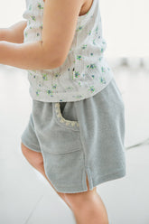 Toddler girl in Avauma Green Tea Milk shorts with floral top, walking indoors